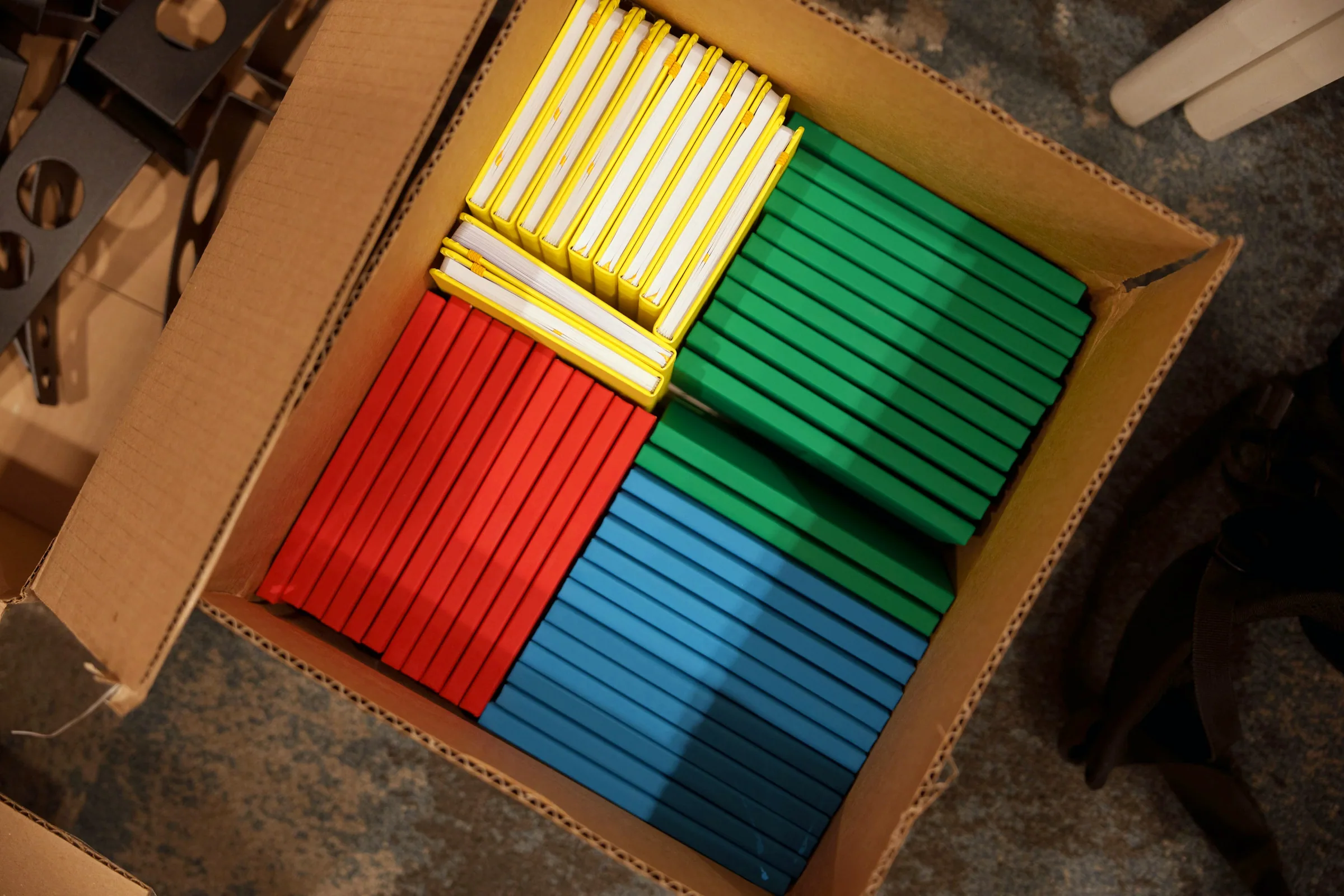 A box of notebooks sorted by Google color