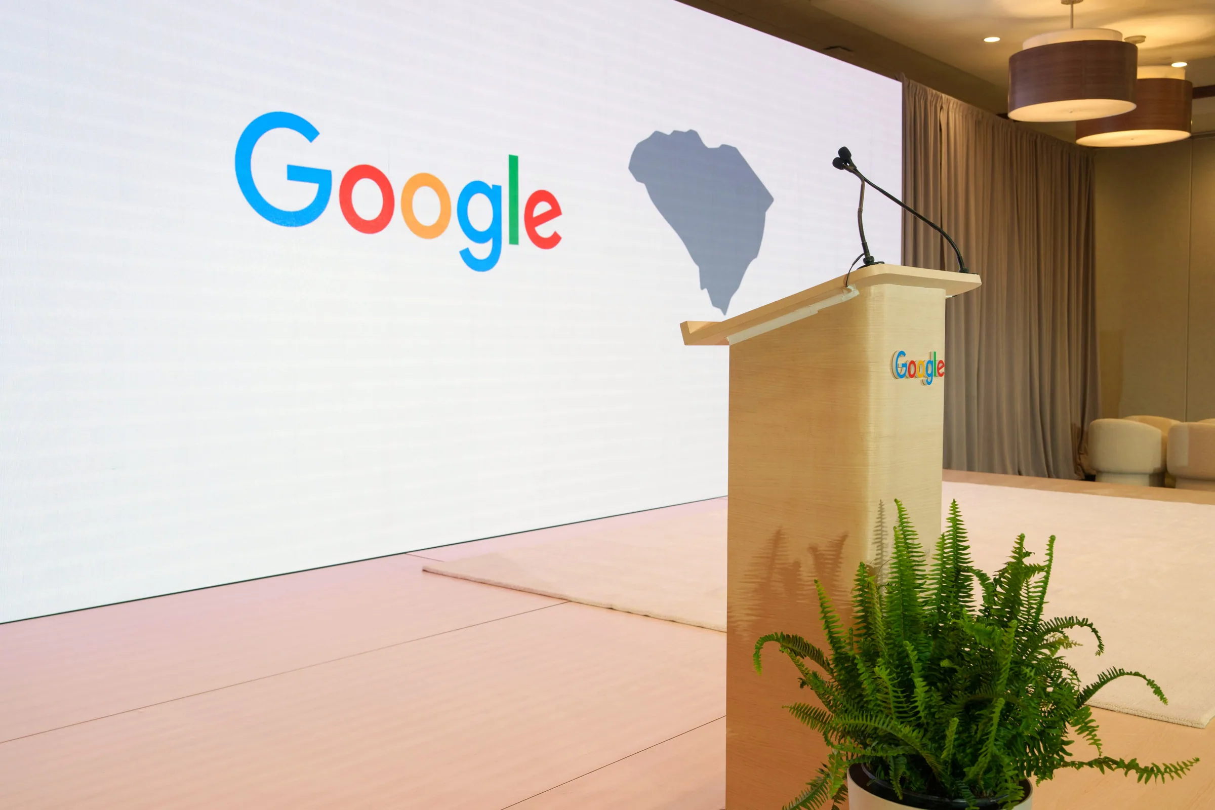 A podium and fern in front of a big Google and South Carolina screen