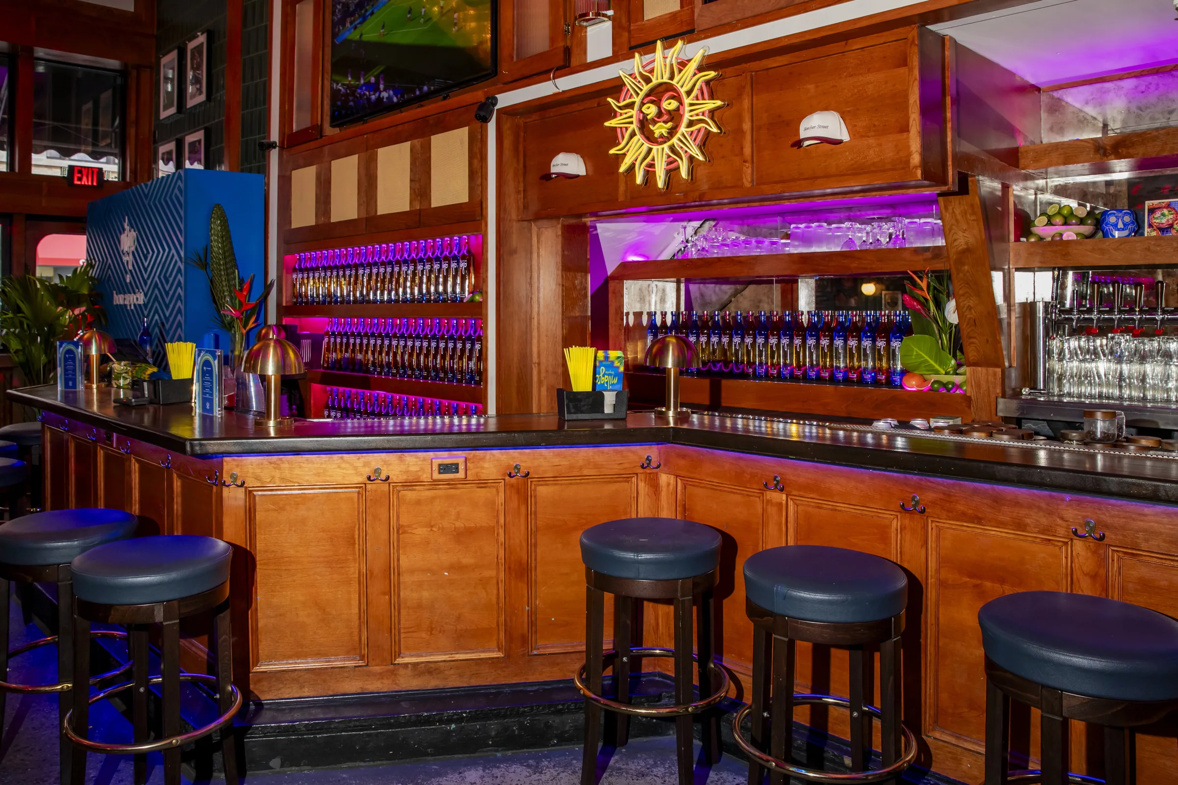 The bar with a gold sun and tequila lit behind it