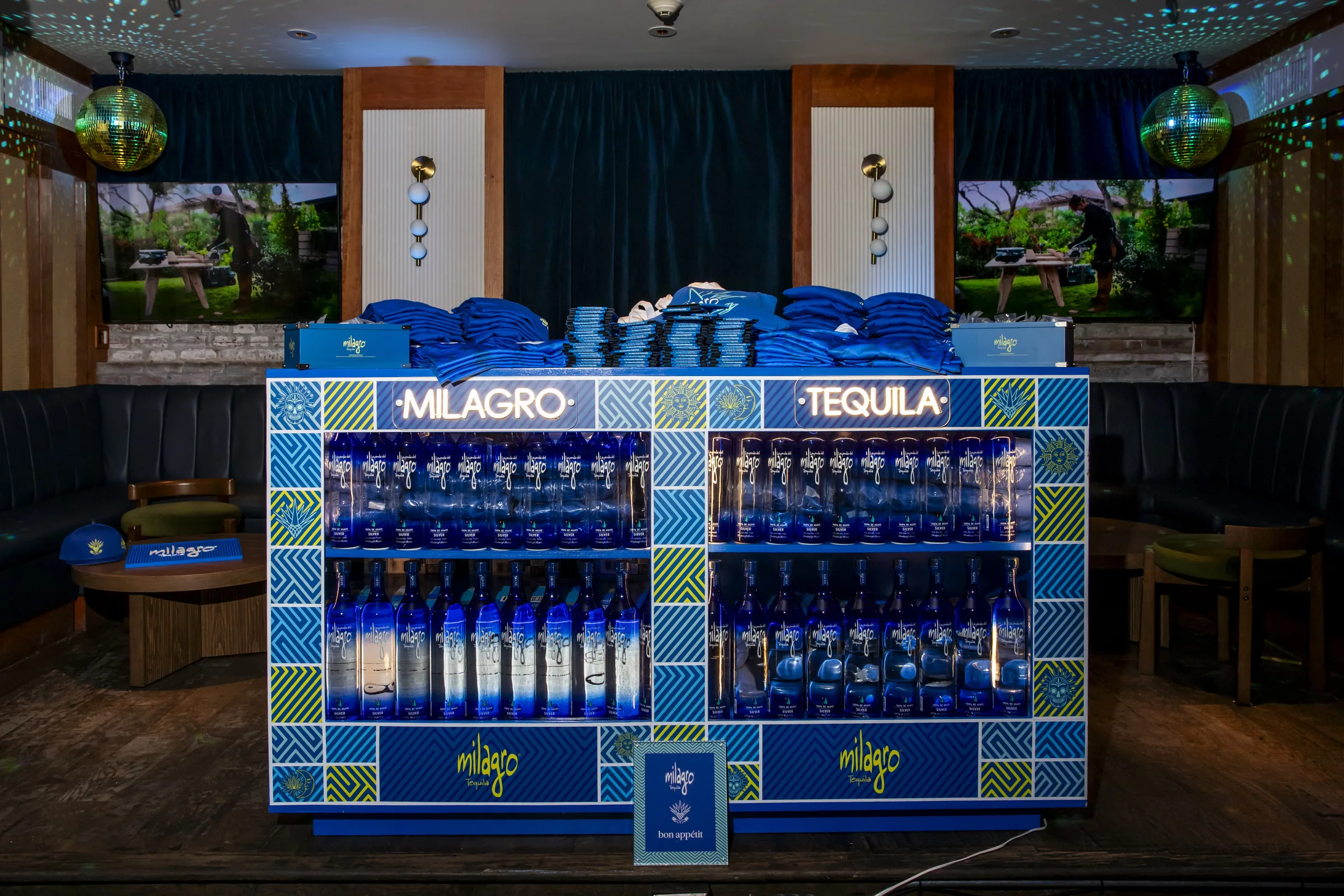 A Milagro Tequila merch bar stacked with blue jerseys
