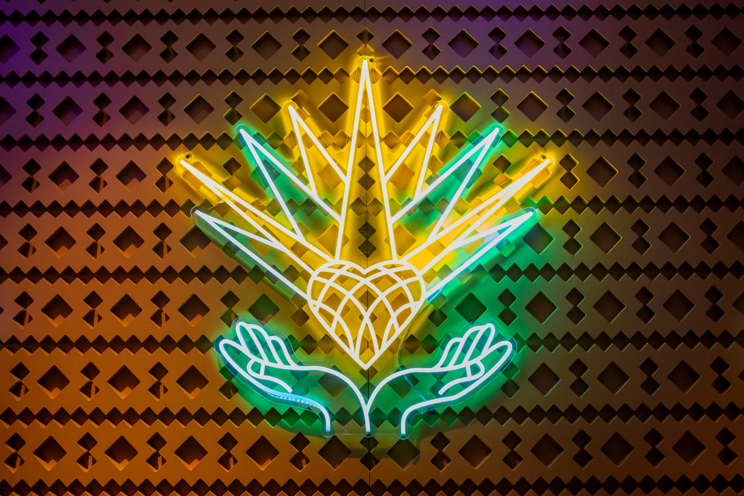 A neon Milagro agave sign on a patterned wall